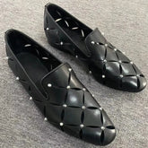 Black leather loafers featuring a laser-cut floral pattern and silver stud embellishments.