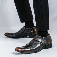 A pair of brown, pointed-toe dress shoes with a side buckle strap and metallic stud accents.