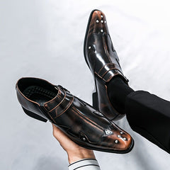 A pair of dark brown pointed-toe dress shoes with metallic stud accents and a slip-on design.