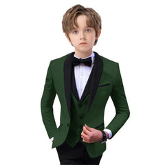 A boy wears a dark green slim-fit tuxedo blazer with a black shawl lapel and matching vest.