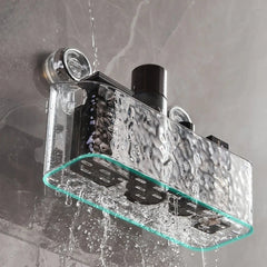 A clear, rectangular suction cup shower shelf mounted on a wall with water flowing over it.