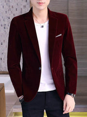 A man wears a burgundy velvet single-breasted blazer with a white t-shirt and black trousers.