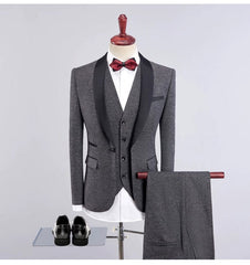 A grey three-piece suit with a black shawl collar, white shirt, and red bow tie on a mannequin.