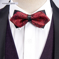 A red paisley patterned bow tie with a black center band worn over a white shirt and vest.