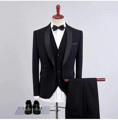 A black three-piece suit featuring a shawl collar jacket, a matching vest, and dress shoes.
