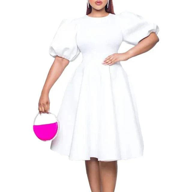 A woman wears a white A-line dress with short lantern sleeves and a high waist.