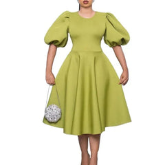 A woman wears a lime green A-line dress with short lantern sleeves and a high waist.