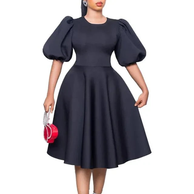 A woman wears a black A-line dress with short lantern sleeves and a high waist.