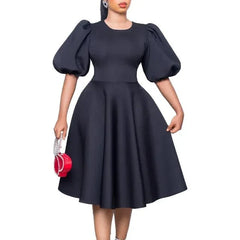 A woman wears a black A-line dress with short lantern sleeves and a high waist.