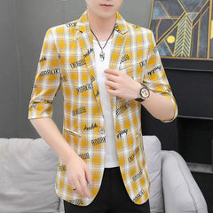 A man wears a yellow and white plaid blazer with half sleeves and black text print.