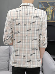 A person wears a beige plaid blazer with half sleeves and black text print on the back.