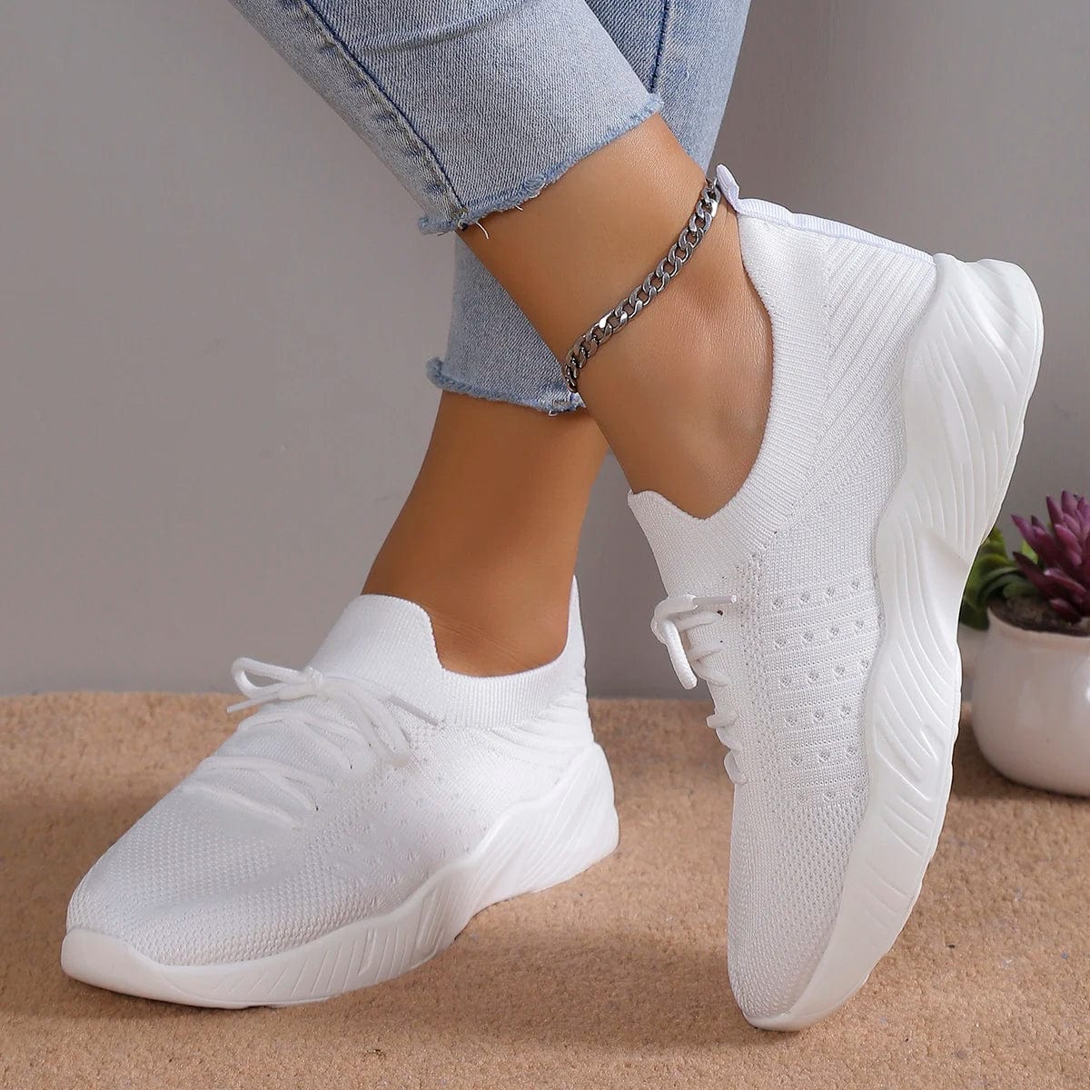 A pair of white mesh lace-up sneakers with a platform sole worn by a person.