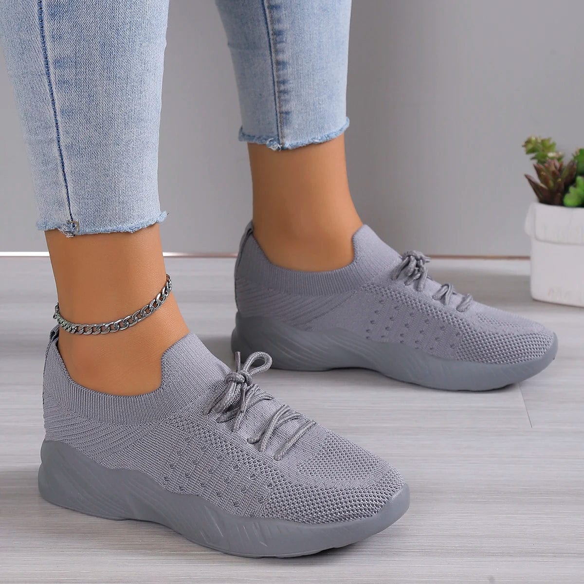 A pair of grey mesh lace-up sneakers with a platform sole worn with light blue jeans.