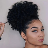 A woman wears a black kinky curly afro puff drawstring ponytail hair extension.