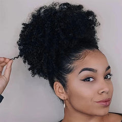 A woman wears a black kinky curly afro puff drawstring ponytail hair extension.
