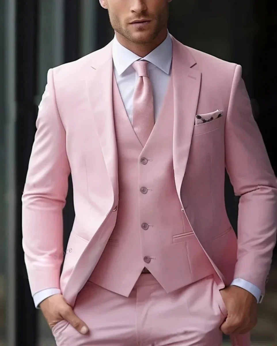 A man wearing a light pink three-piece suit with a matching vest, jacket, and tie.
