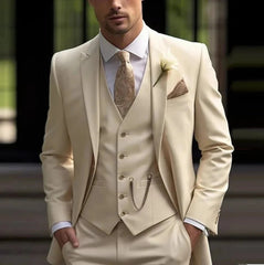 A man wearing a cream-colored three-piece suit with a patterned tie and a pocket watch chain.