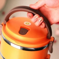A hand holds the brown handle of an orange, stainless steel thermal lunch box.
