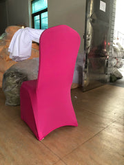 A bright pink, one-piece stretch chair cover fits snugly over a banquet chair.