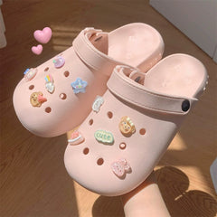 A pair of light pink EVA clogs decorated with various colorful cartoon charms.