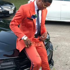 A man wears a slim-fit orange two-piece suit with a dark stripe and peaked lapels.