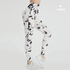 A woman wears high-waisted, ankle-length white leggings with a black tie-dye pattern.