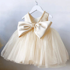 A sleeveless cream-colored toddler dress featuring a large satin bow and pearl-trimmed neckline.
