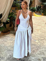 A woman wears a white two-piece set featuring a sleeveless V-neck bodysuit and a tie-waist skirt.