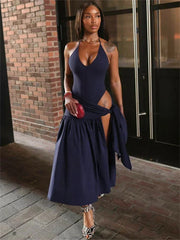 A woman wears a navy blue two-piece set featuring a sleeveless V-neck bodysuit and a pleated skirt.