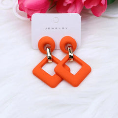 A pair of bright orange dangle earrings featuring a circular stud connected to a hollow square.