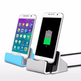Two smartphones sit in silver and blue USB-C desktop charging docks with attached cables.
