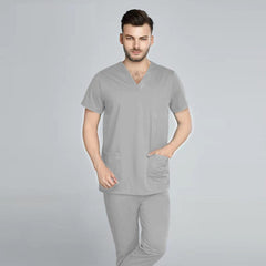 A man wearing a light gray V-neck scrub top and matching jogger-style pants.