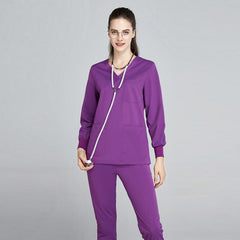 A woman wearing a purple V-neck scrub top and matching jogger-style pants with a stethoscope.