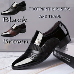 A pair of black pointed-toe slip-on dress shoes with a textured panel and metallic buckle detail.