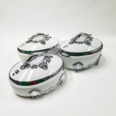 A set of three white oval thermal food containers with ornate silver handles and shell-shaped feet.
