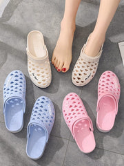 A pair of feet wearing beige rubber cave shoes surrounded by additional blue and pink pairs.