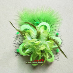 A lime green floral hair clip featuring layered fabric petals, feathers, and a black mesh veil.
