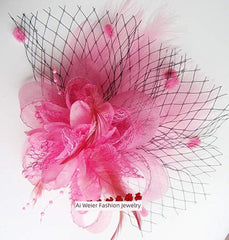 A pink floral hair clip featuring feathers and a black netting veil.