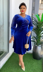 A woman wears a royal blue velvet knee-length dress with long sleeves and silver beaded accents.