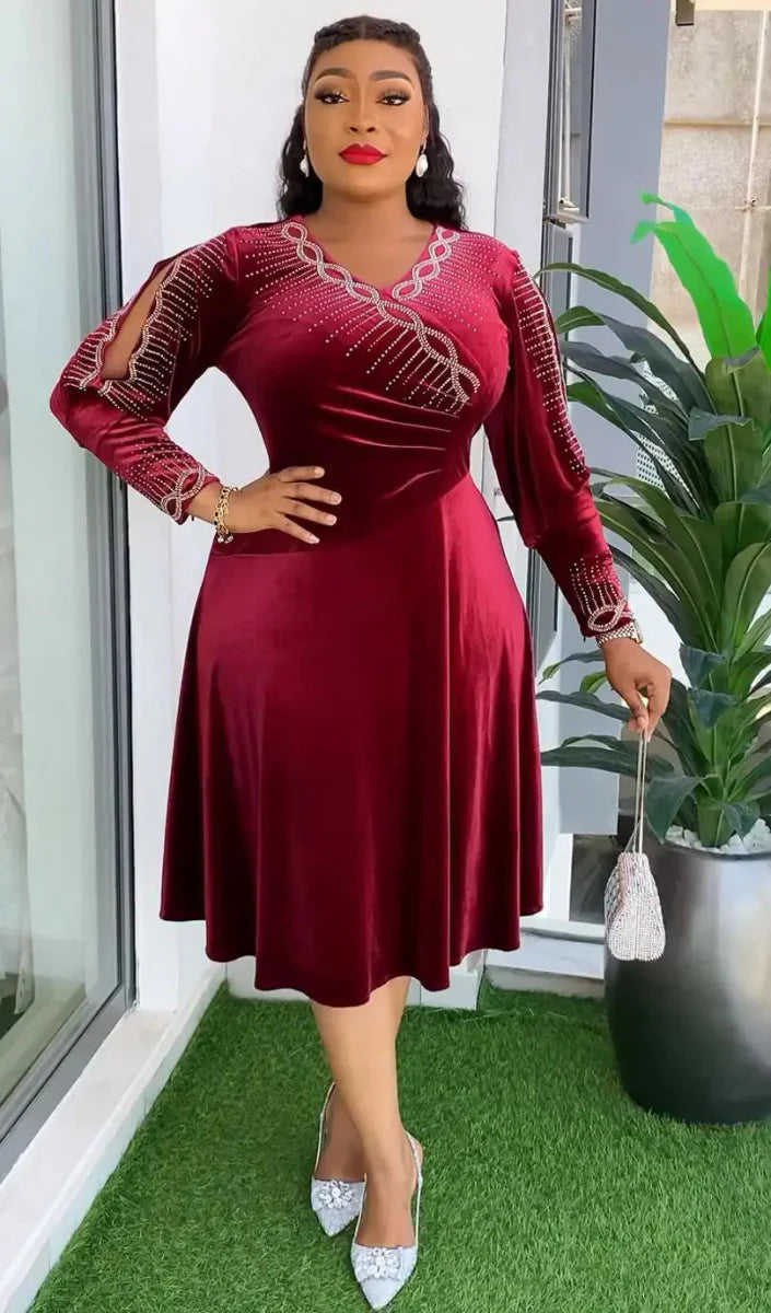A woman wears a long-sleeved, knee-length burgundy velvet dress with rhinestone embellishments.