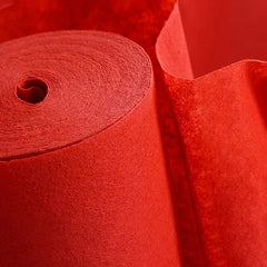 A roll of vibrant red non-woven fabric carpet with a textured surface.
