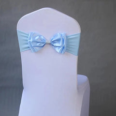 A light blue satin bow tie chair sash with a rhinestone center on a white chair cover.