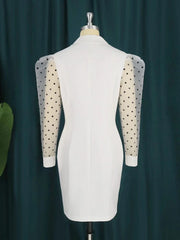 A white mini blazer dress with sheer, polka-dot puff sleeves on a mannequin.