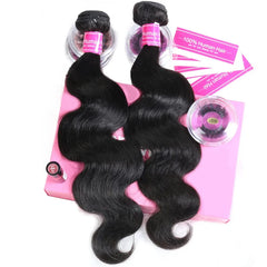 Two bundles of black body wave human hair extensions with a pair of eyelashes on a pink box.