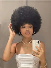 A person wears a short, fluffy black afro wig with a natural, voluminous texture.
