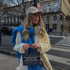 A woman wears a bright blue, thick, solid-colored cashmere winter scarf draped over her shoulders.