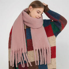 A woman wears a thick, fluffy, solid pink scarf with long tassels.