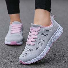 A pair of grey and pink breathable mesh sneakers with lace-up closures.