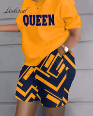 A woman wears a yellow short-sleeved t-shirt with the word Queen printed on it and matching navy shorts with a yellow geometric pattern.