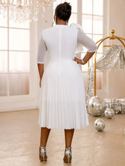A woman wears a white knee-length A-line dress with half sleeves, ruffles, and a pleated skirt.